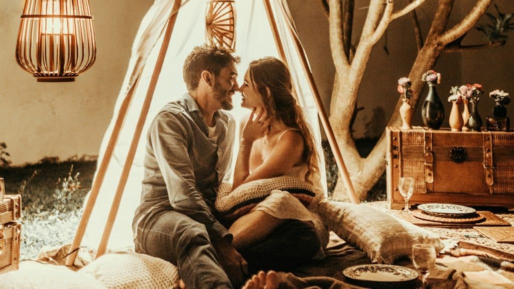 A smiling man and woman inside a tipi tent.