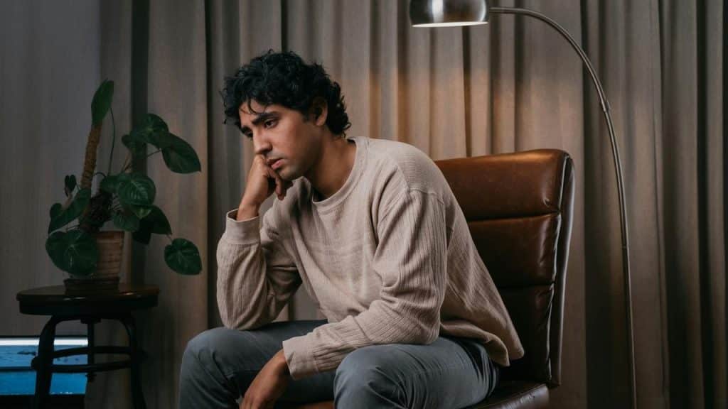 A thoughtful man sitting in a chair with his head resting on his hand.