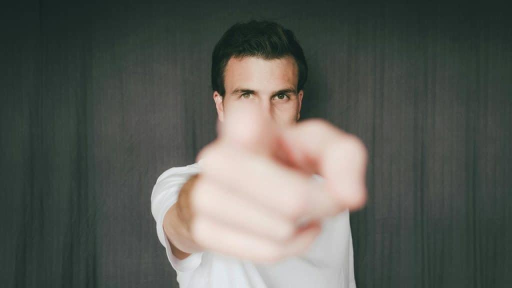 A man pointing directly toward the camera with an intense gaze.