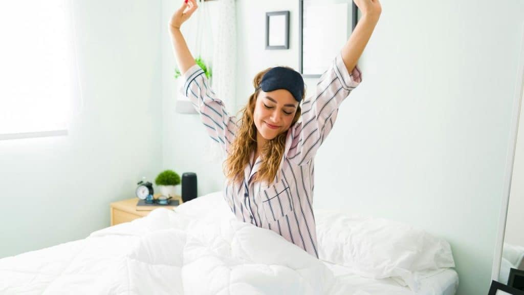 A woman stretching in bed after waking up.