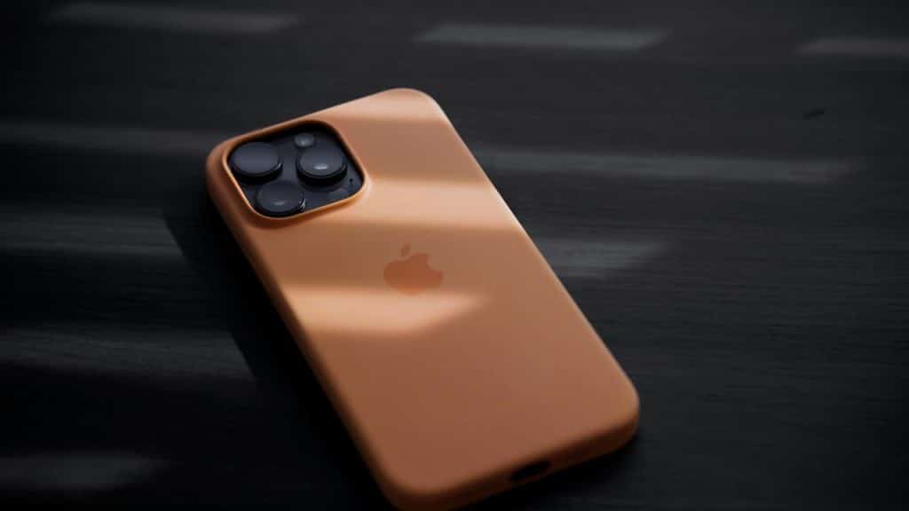 A smartphone with a tan protective case resting on a dark surface.