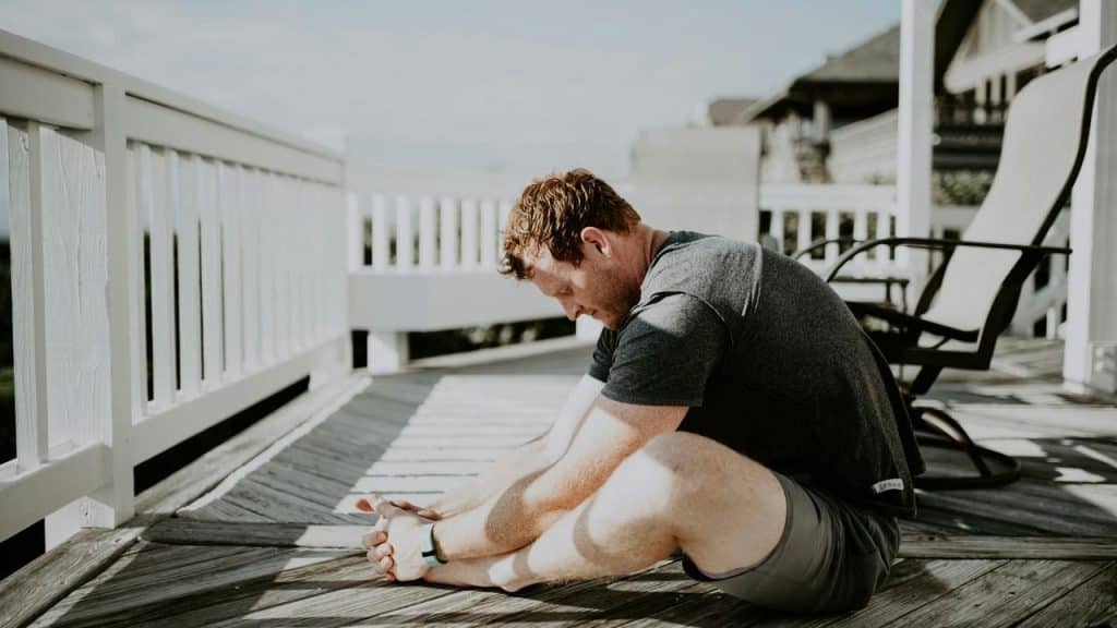 A man stretching on a wooden deck outdoors.
