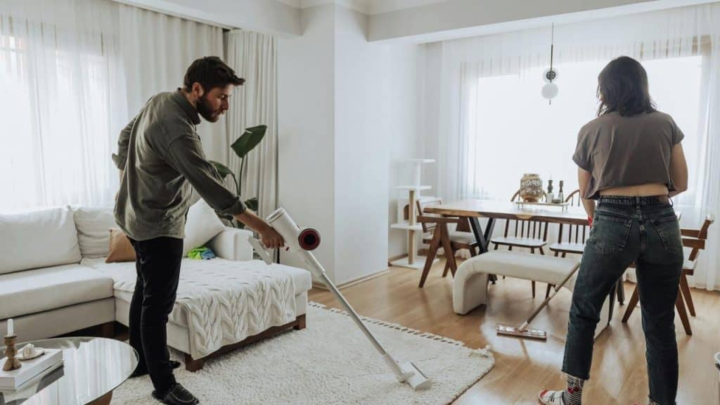 A couple cleaning their living room together.