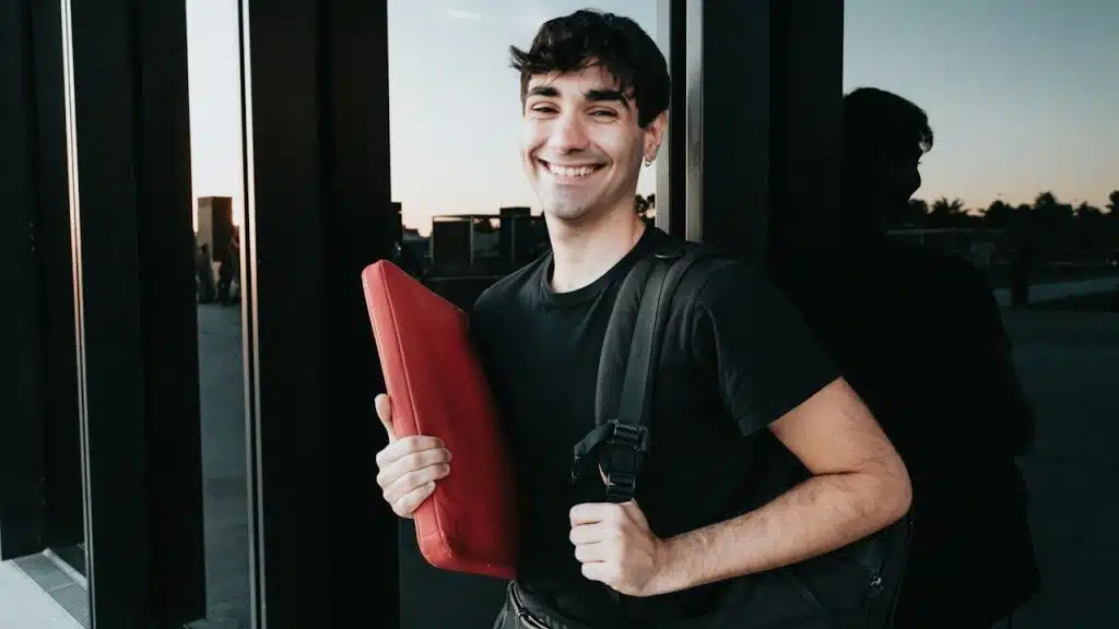 A man holding a red object in front of a window.