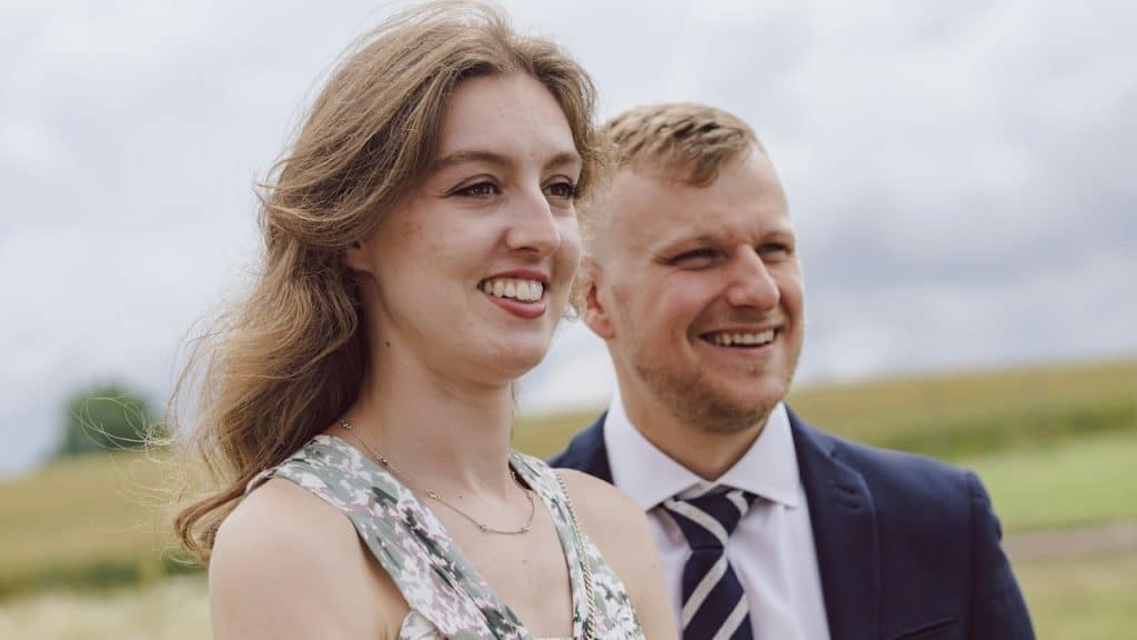A man in a suit and tie is standing next to a woman.