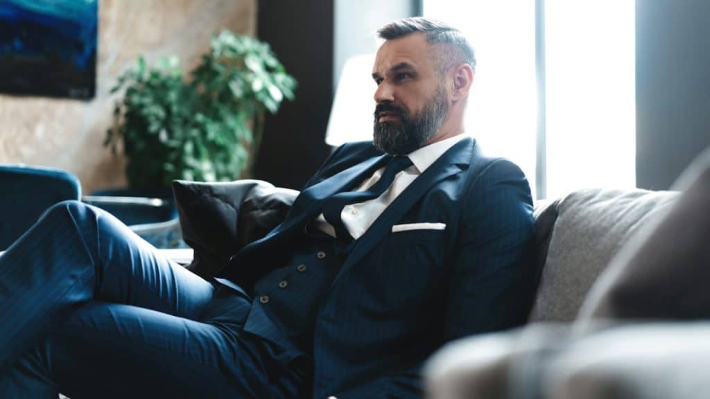 A confident, concentrated, thoughtful, handsome businessman thinking while sitting in his modern office about a business concept while sitting on a sofa.