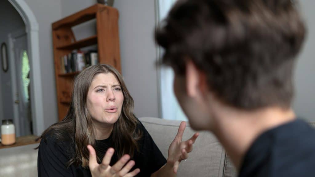 A woman sitting on a couch talking to a man.