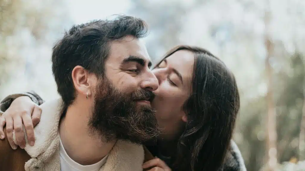 A man and a woman kissing in the woods.