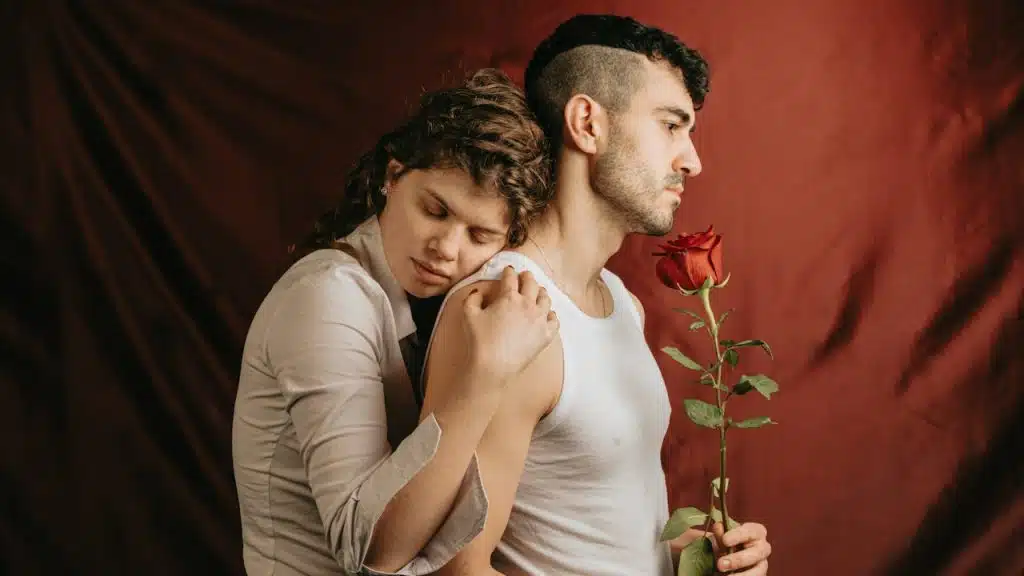 A man holding a woman while she holds a rose.
