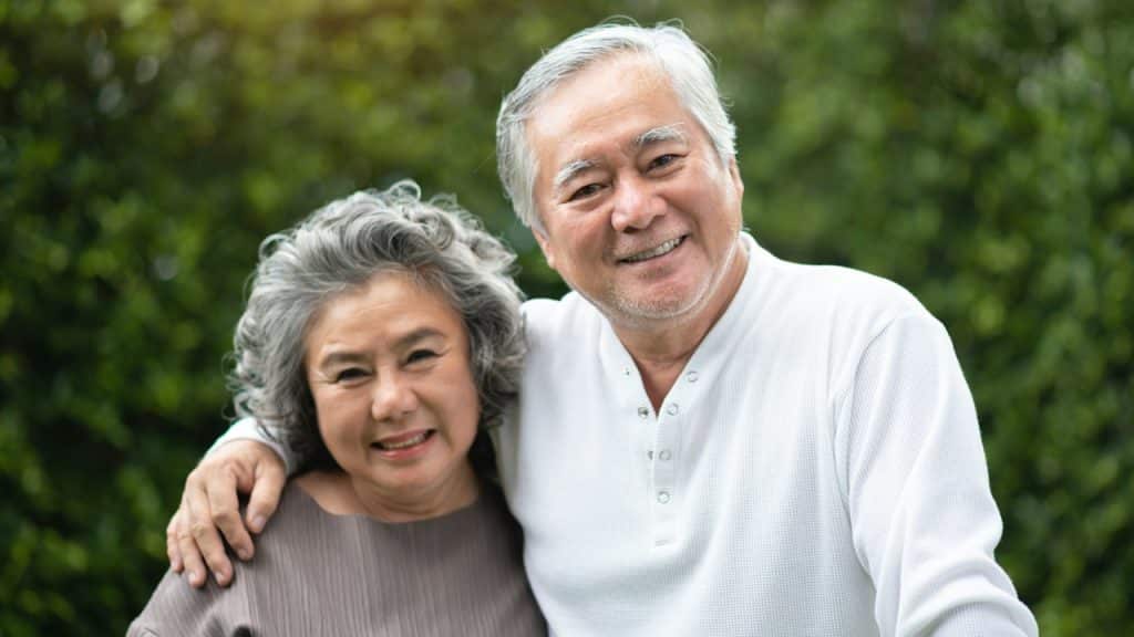 asian-senior-couple-smiling-and-looking-to-camera-at-the-park.