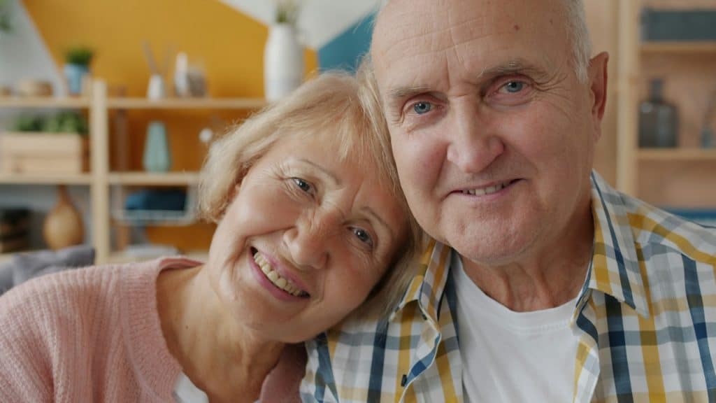 Elderly couple smiling indoors.