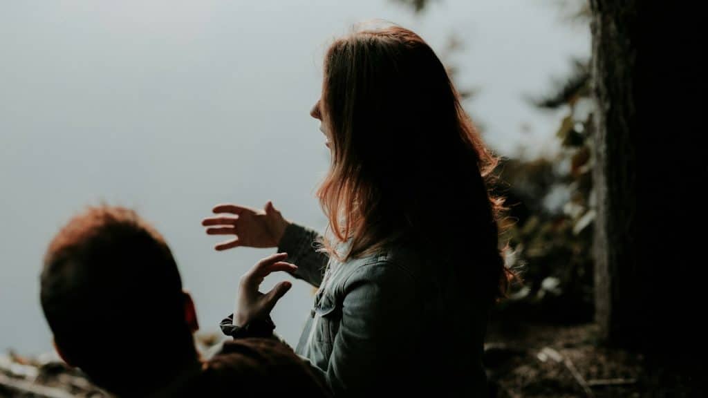 A woman talking to a man sitting next to her.