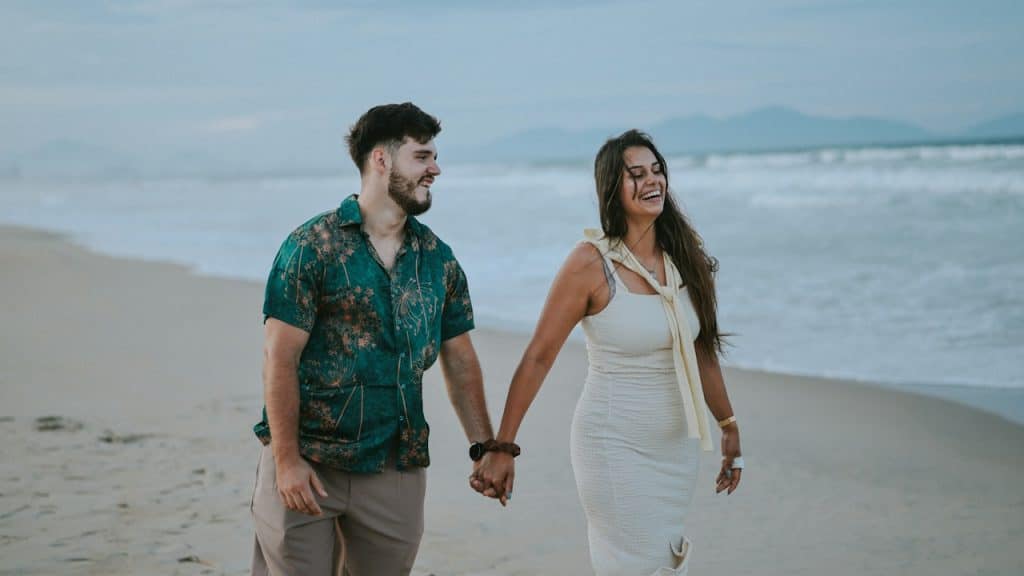 A couple holding hands walking on a beach.