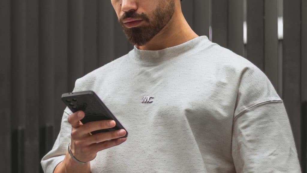 A man looking at his smartphone while standing outdoors.