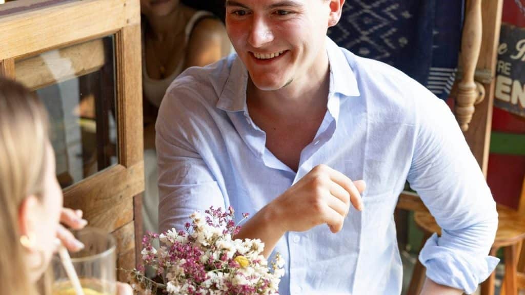 A man smiling while talking across a café table.