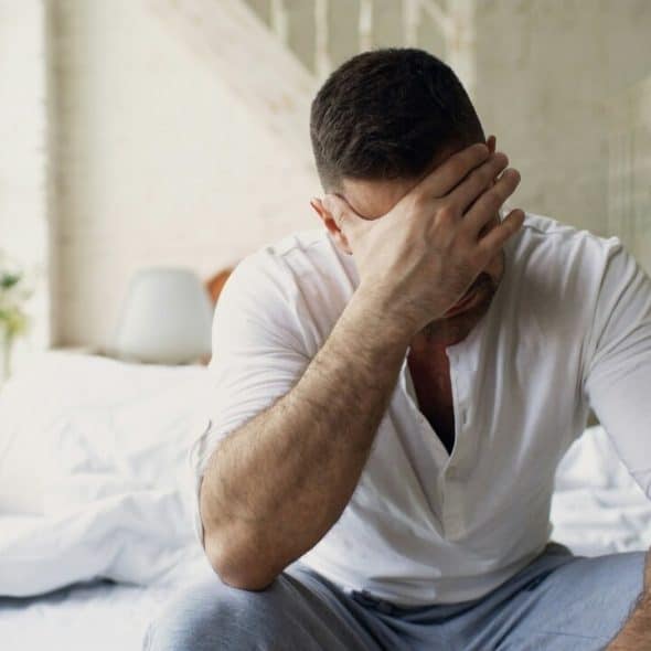A man looking upset while his wife sleeps