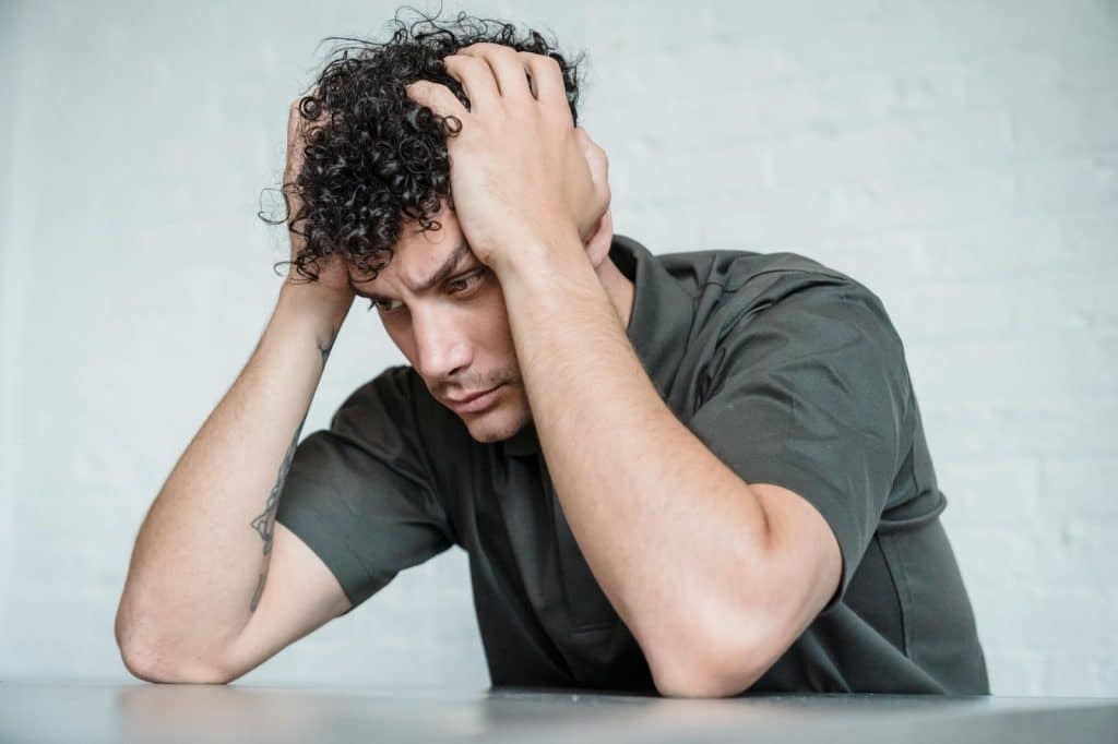 A man alone and holding his head