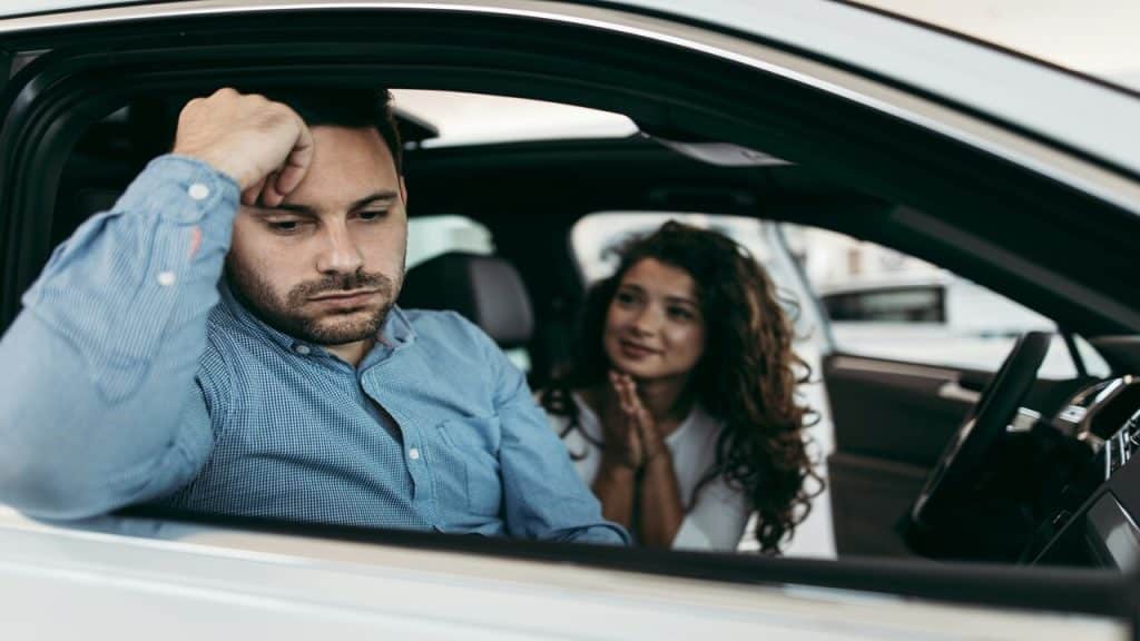 A man looking sad while his wife looks at him