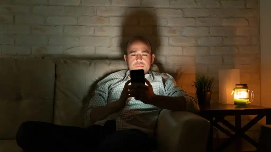 A man sits on a light-colored sofa with his head in his hand while a woman looks away.