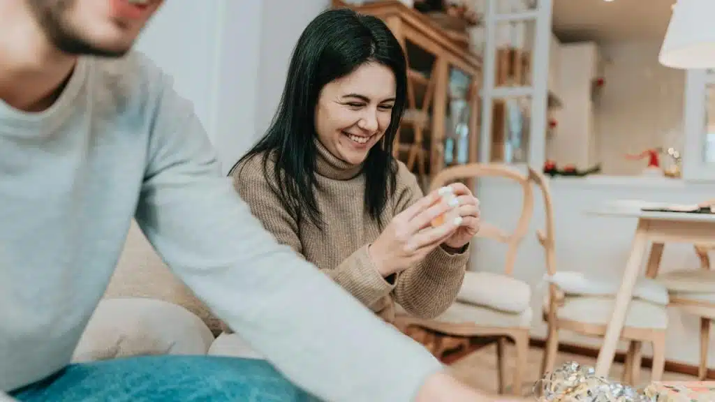A woman smiling while holding a small decorative object indoors.
