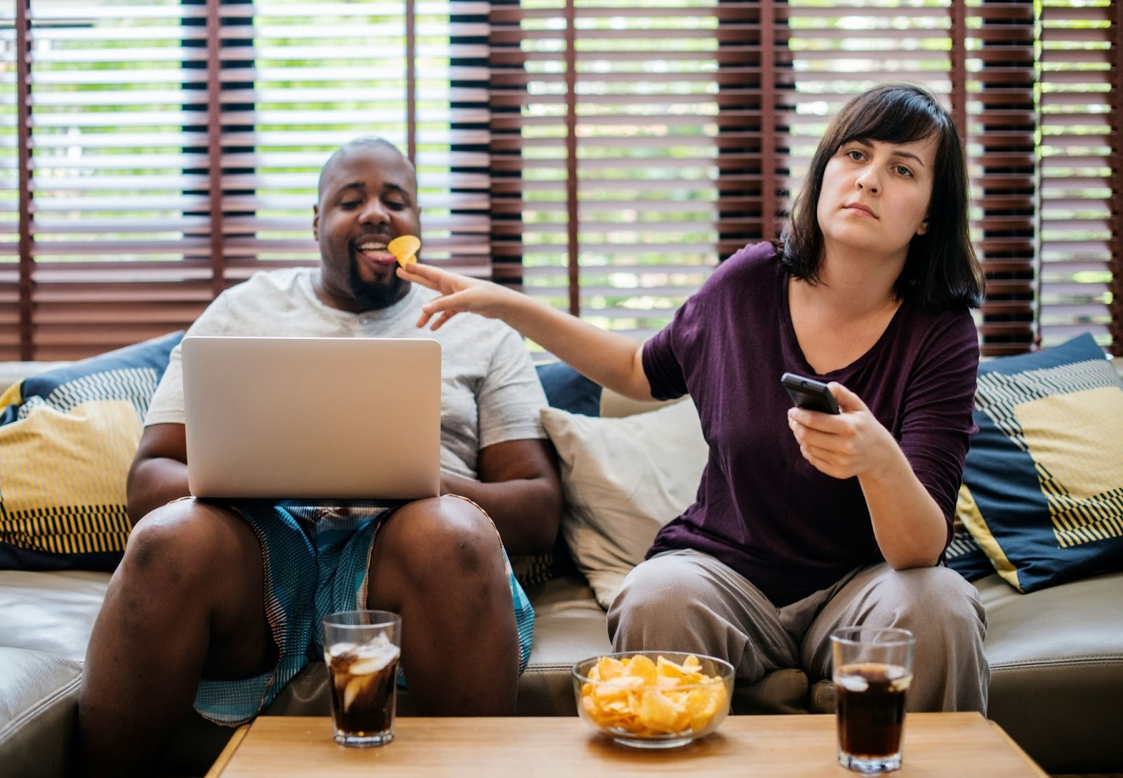 A woman watching a tv and a man using a laptop 