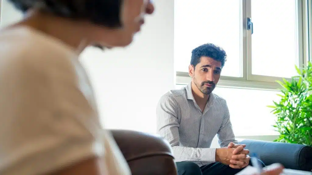 A man looking seriously at a person, who is blurred in the foreground.