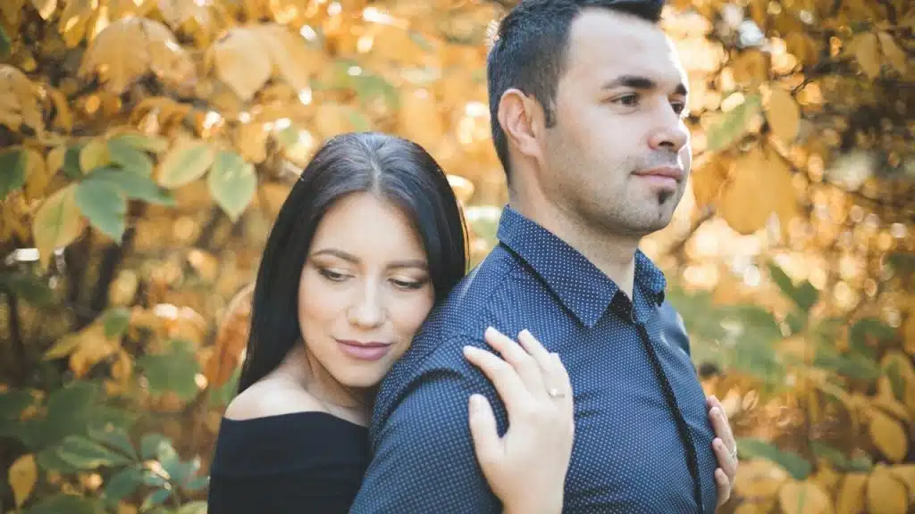 A woman holding a man close to her from behind.