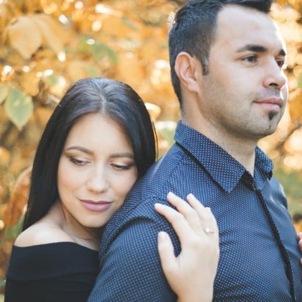 A woman holding a man close to her from behind.