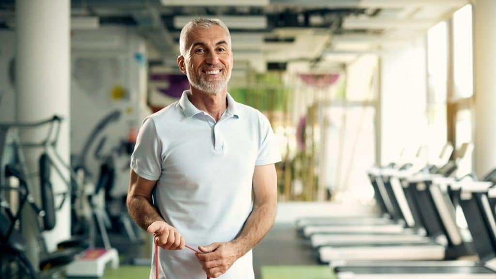 A man smiling and working out in a gym.