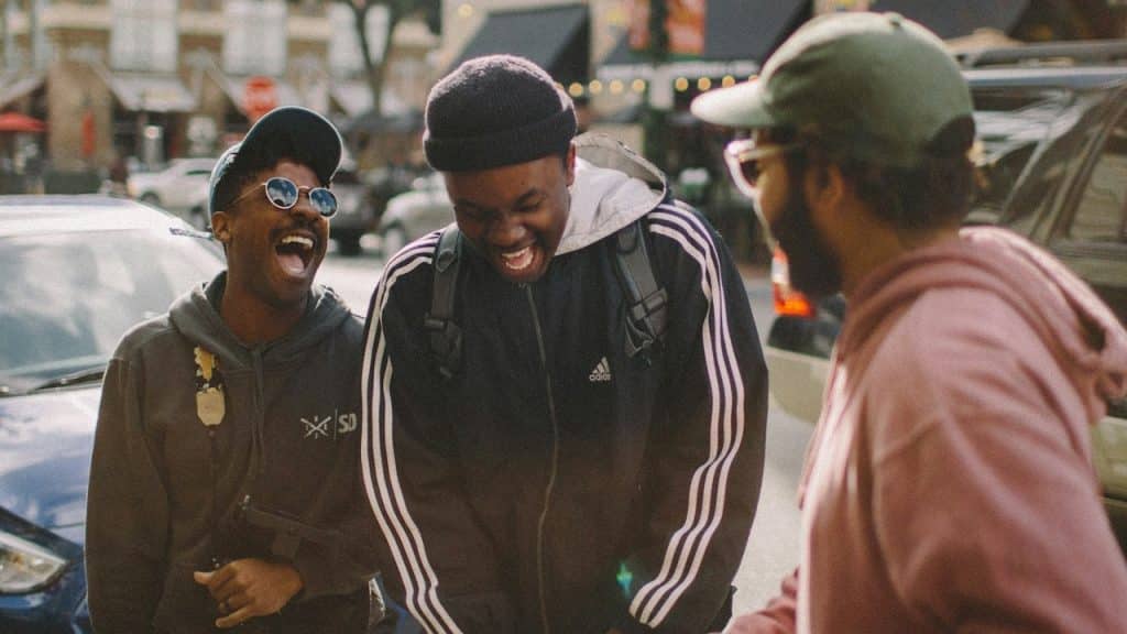 A group of friends standing on the street and laughing together.
