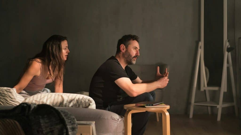 A woman complaining to her husband while he is sitting silent.