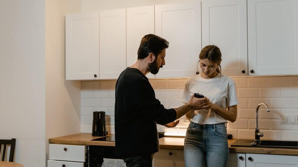 A serious man taking the phone from her wife’s hand who is being very upset.