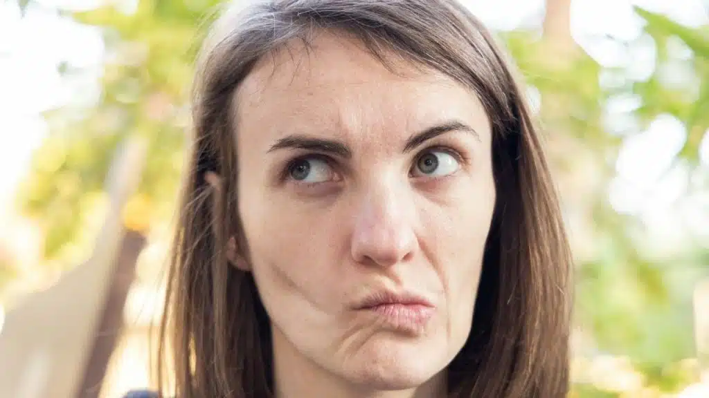 A woman with brown hair looking upward and sideways with a skeptical, pursed lip expression.