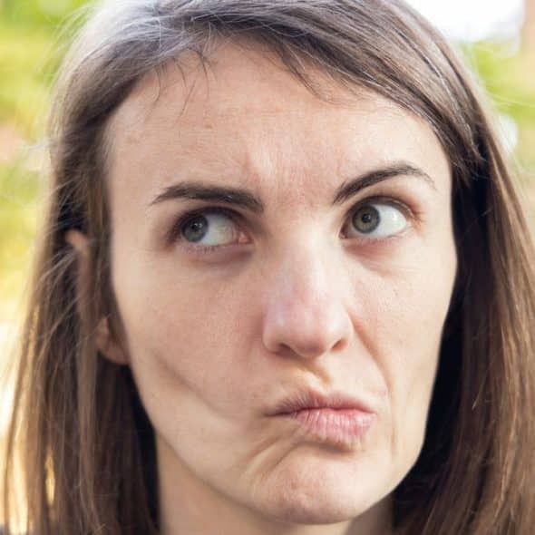 A woman with brown hair looking upward and sideways with a skeptical, pursed lip expression.