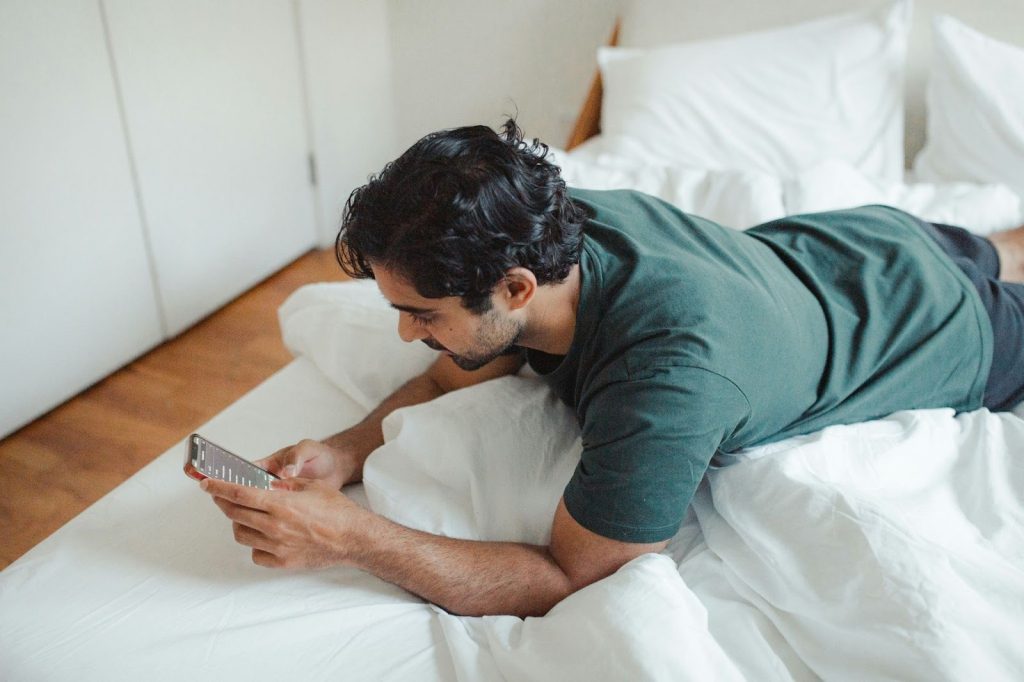 A man laying in bed and reading messages