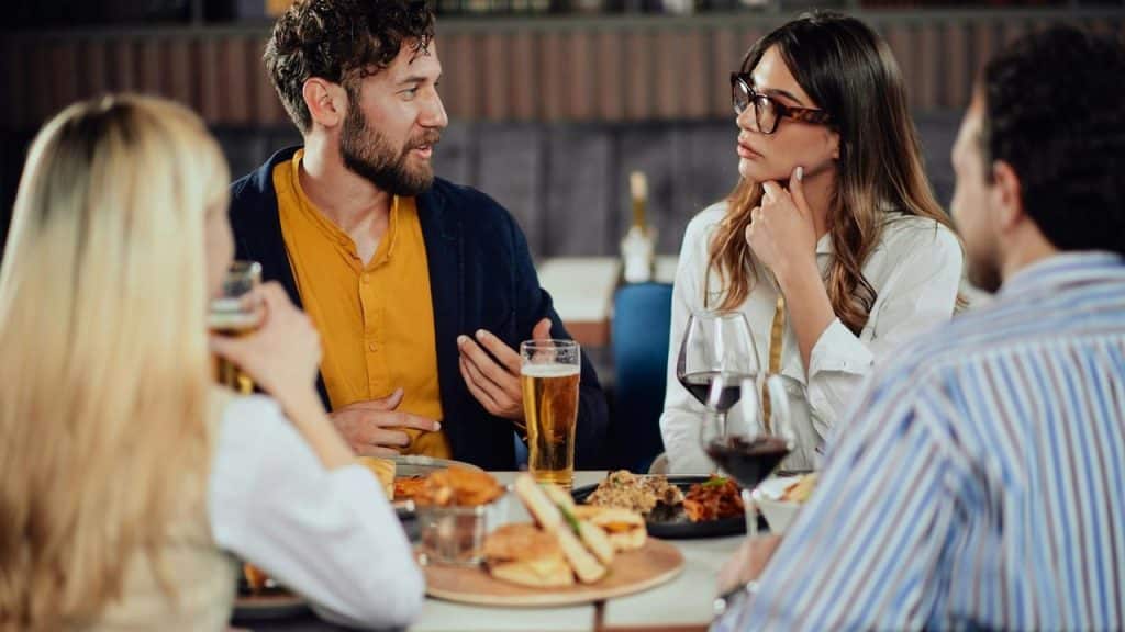 A group of friends talking and drinking at a restaurant table.