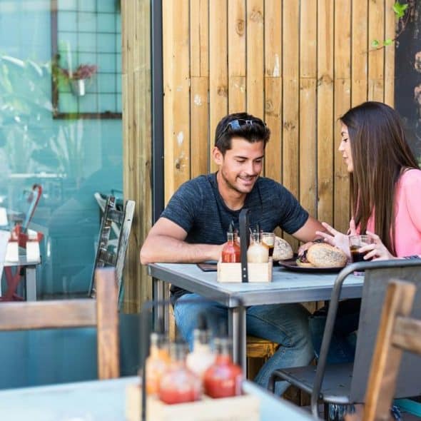 A man and a woman eating lunch together at an outdoor café table.