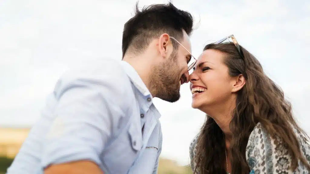 A bearded man smiling and touching noses with a smiling woman.