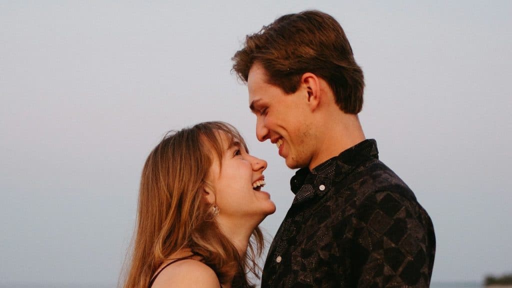A woman smiling while looking upwards in a smiling man’s face.