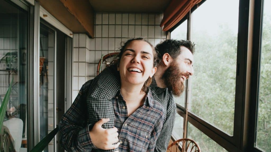 A bearded man holding a woman tightly while they both laugh.