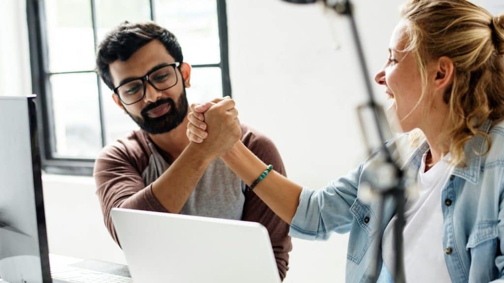 Computer programmer friends holding hands after running a code.
