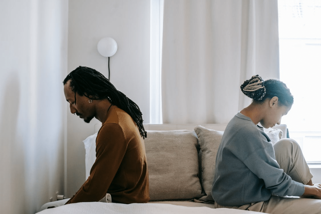 Concerned black couple sitting on bed in misunderstanding