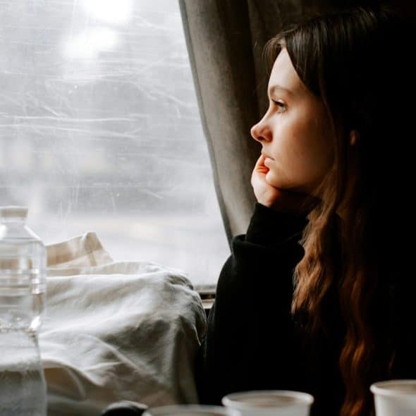 A heartbroken woman looking out of the window of a train.