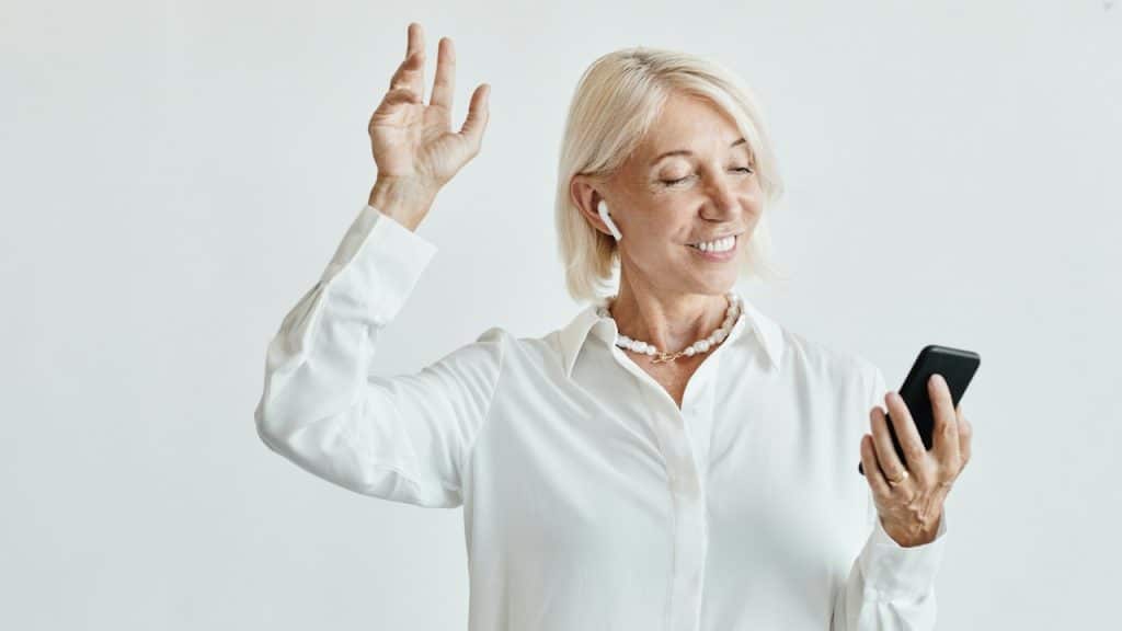 A woman listening to a song on her phone while wearing earbuds.