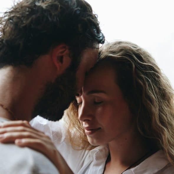A couple with closed eyes touching foreheads and having a tender moment.