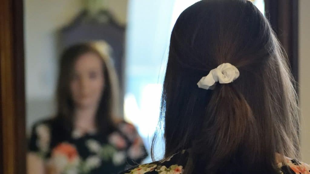 A woman looking at her reflection in the mirror.