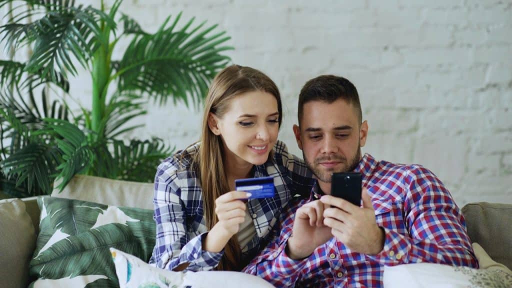A couple is about to buy something with the woman’s credit card on the man’s phone.