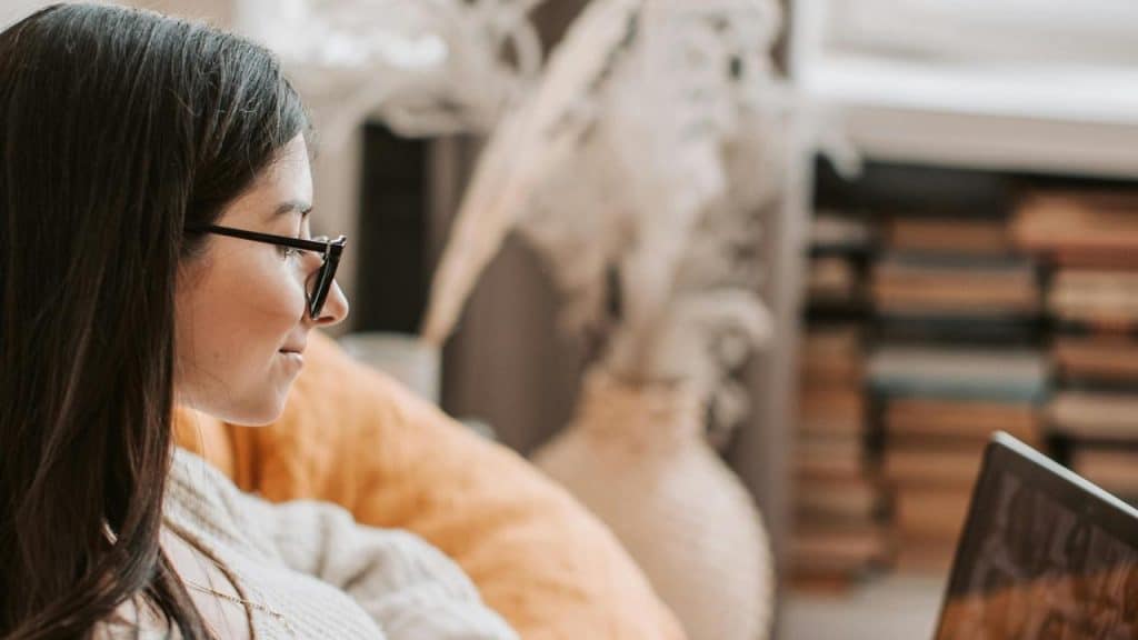 A woman wearing glasses using a laptop indoors.