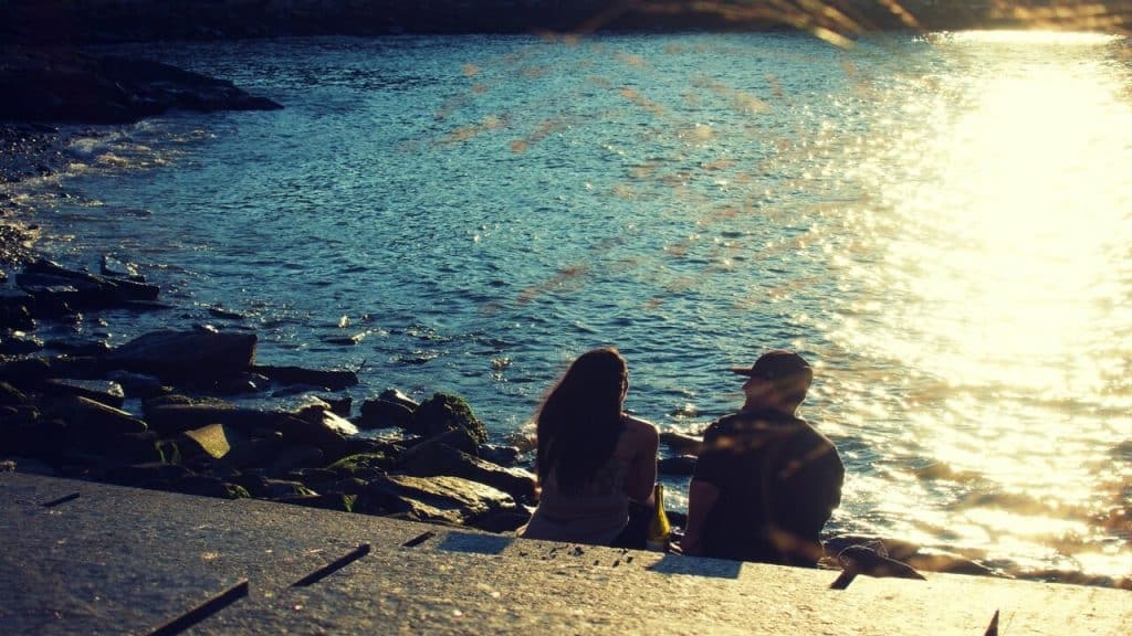 A couple sitting by a body of water