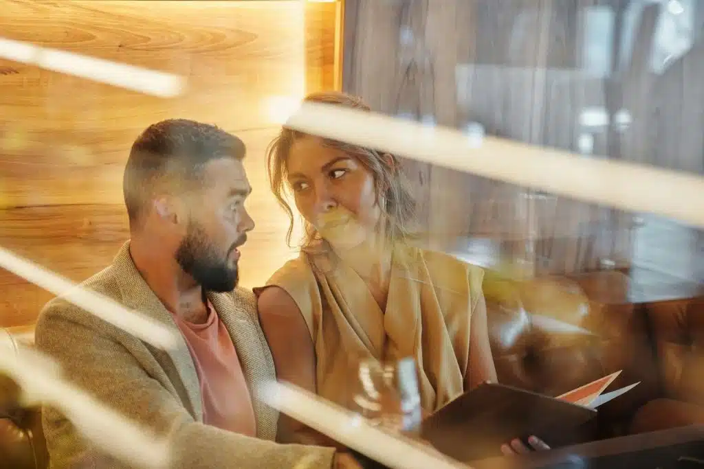 The woman holding the menu is looking at the man